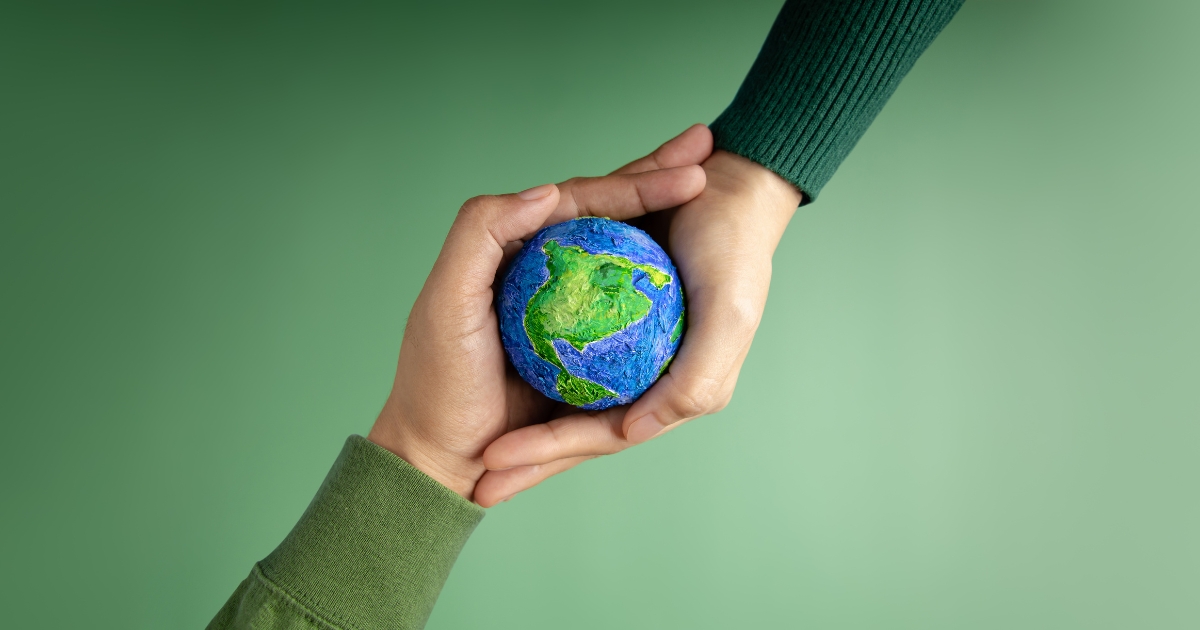 Two people's hands holding a small Earth ball. 10 Tips For A More Sustainable Business.