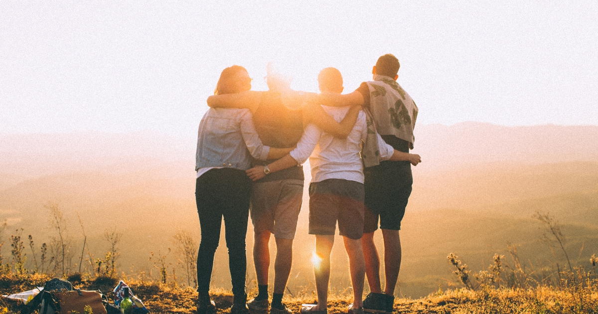 Four people embracing and looking at the sunset. 4 Sustainable Team Bonding Activities For Your Business.