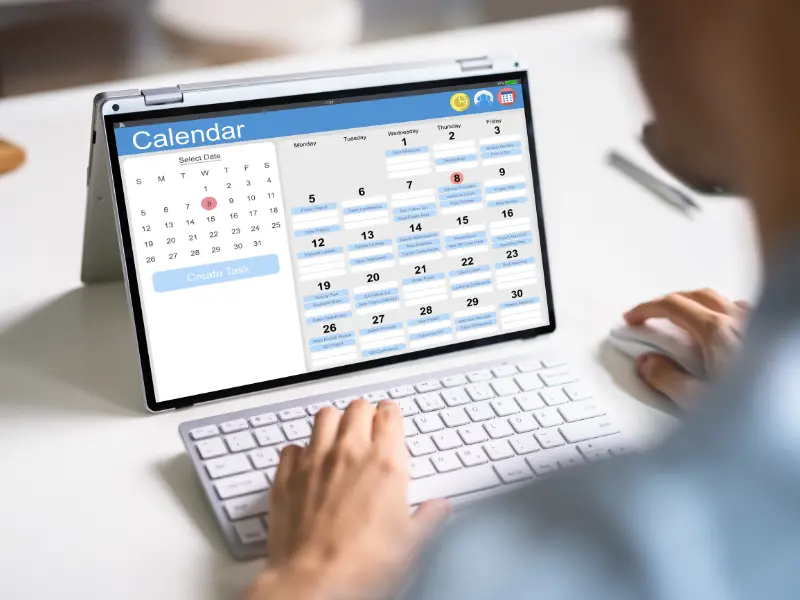 A person sat at a desk looking at a tablet with a booking app open