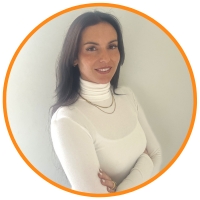 Brown haired woman smiling and wearing a creamy white sweatshirt