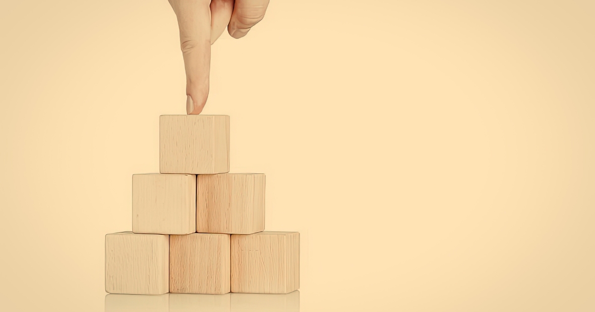 Image of small foundation wooden blocks and finger pointing down from the top
